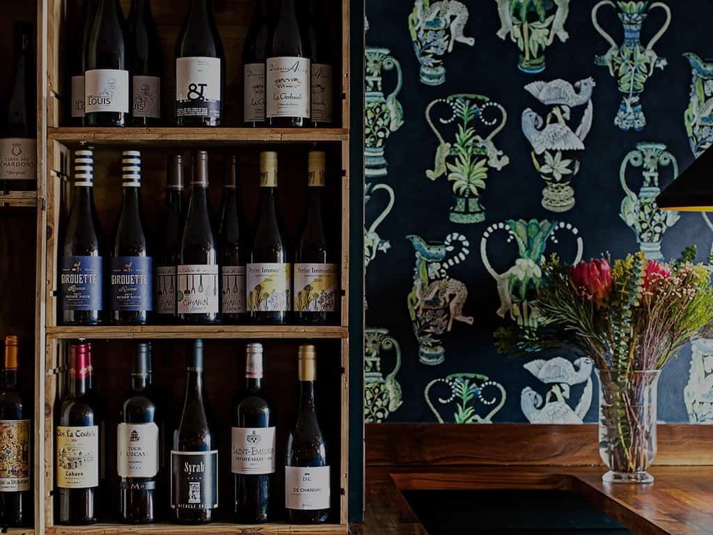 The wine rack against the vases wallpaper